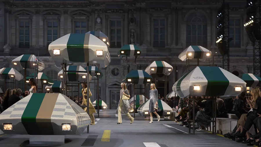 Desfile de Louis Vuitton primavera-verano 2027 en la Cour Carrée del Louvre: modelos entre elementos de decorado iluminados