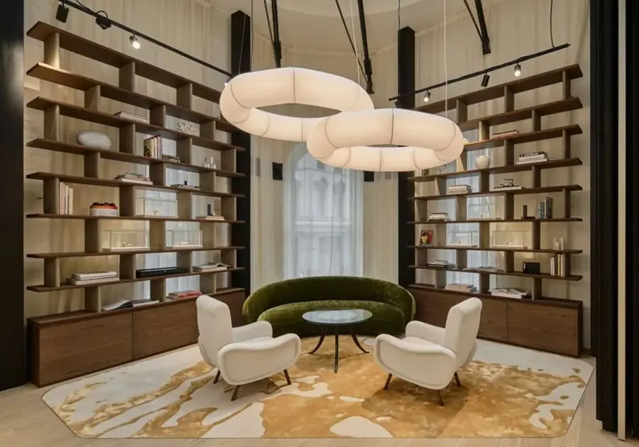 Salón con estanterías de madera, butacas blancas, un sofá verde y lámparas en forma de anillo en la boutique de Montblanc en Sídney
